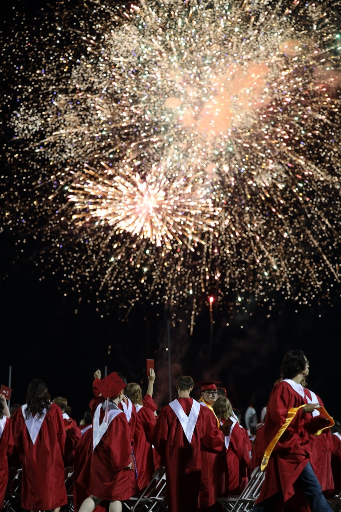 graduates looking up at fireworks