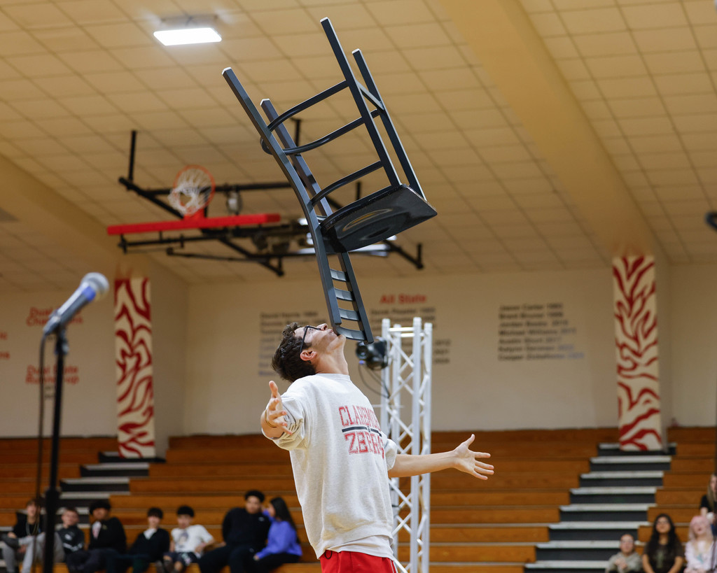 student balancing a chair on his chin