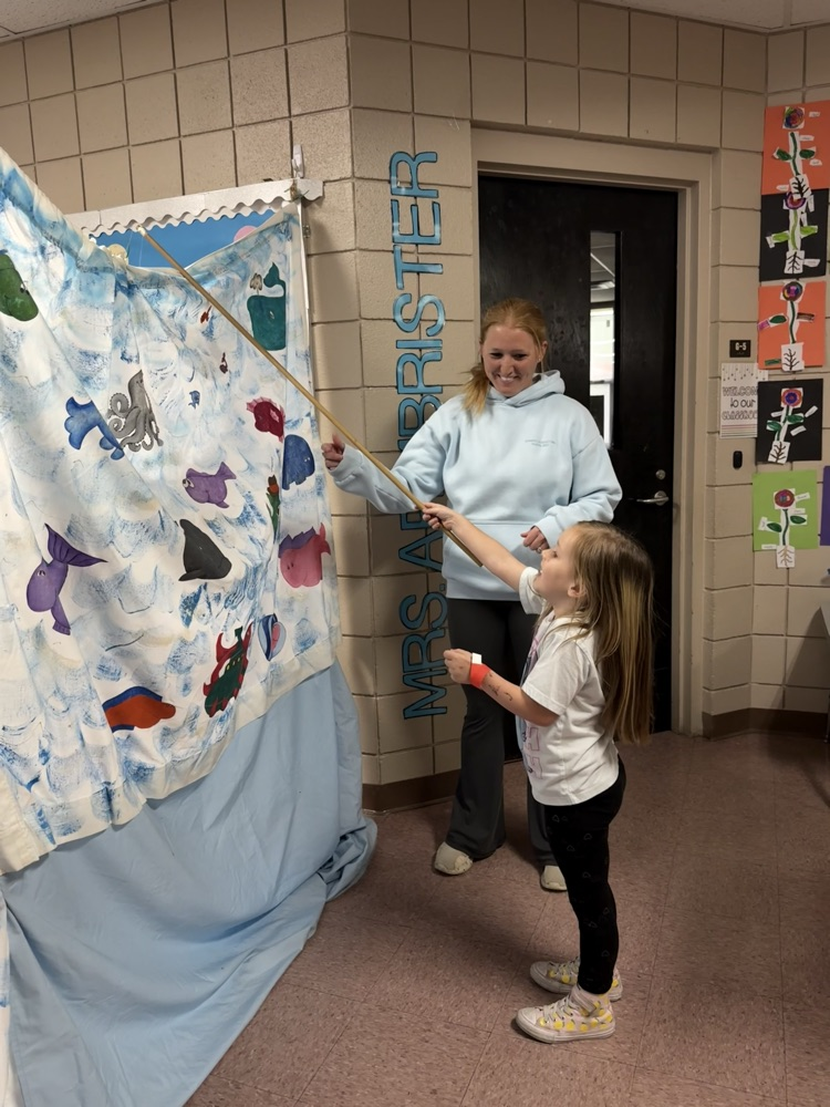 student playing a tossing game with teacher in background