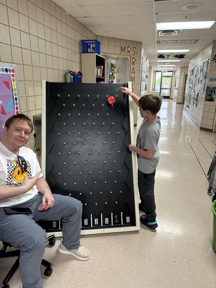 teacher, smiling at camera while student plays game