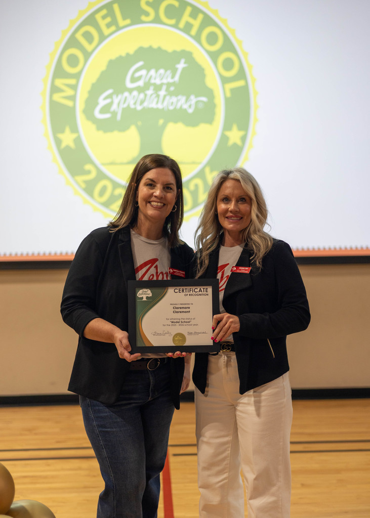 principal and ap smiling, holding award