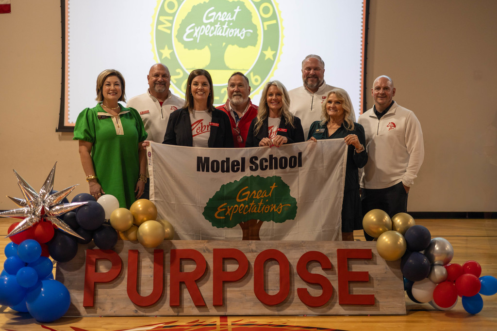 staff smiling at assembly for photo