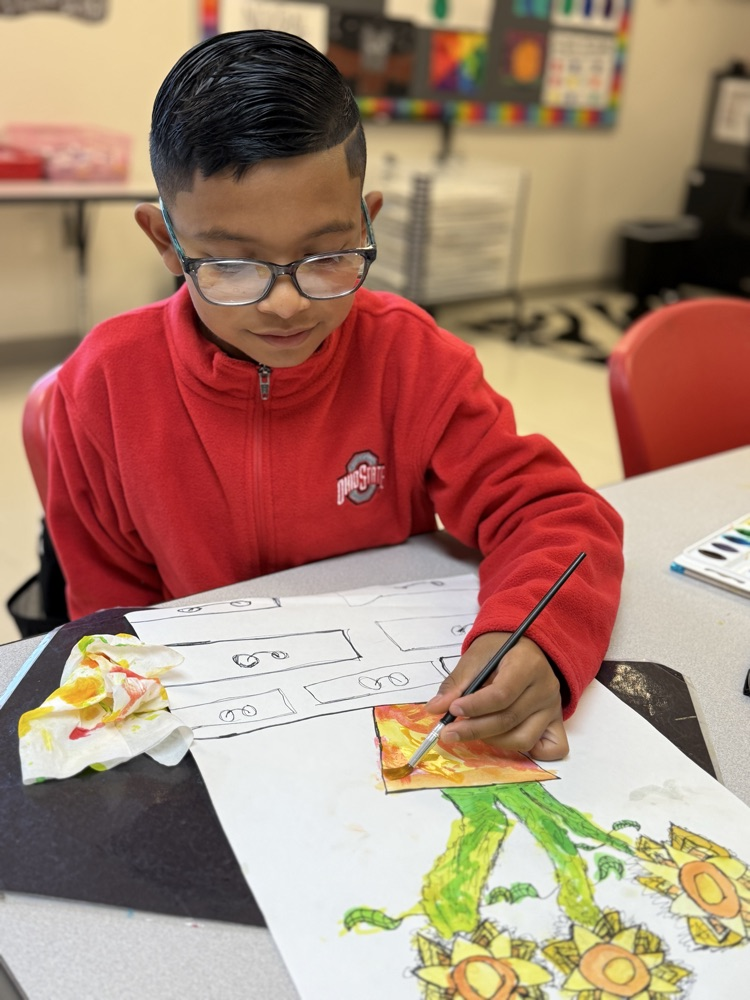 Student painting with a smile on his face in art class.