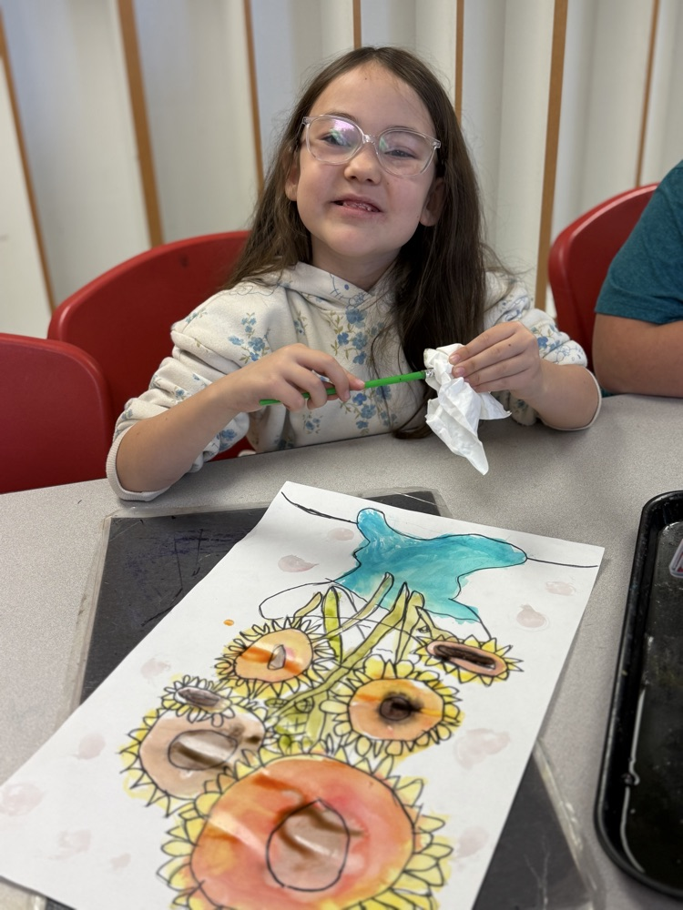 Student smiling as she cleans her paint brush.