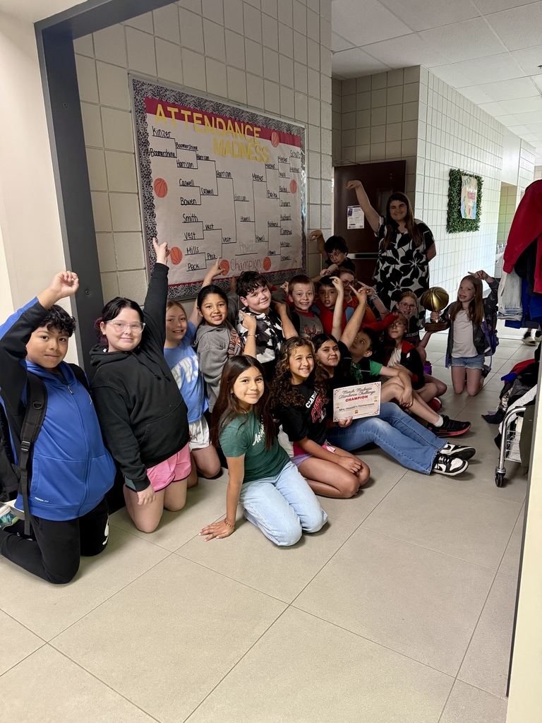 mrs howells class smiling and pointing to the winning teacher  because they won the attendance madness