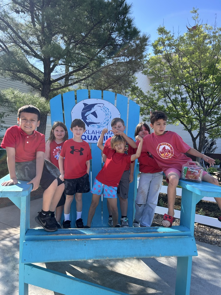 students posing for photo on big chair 