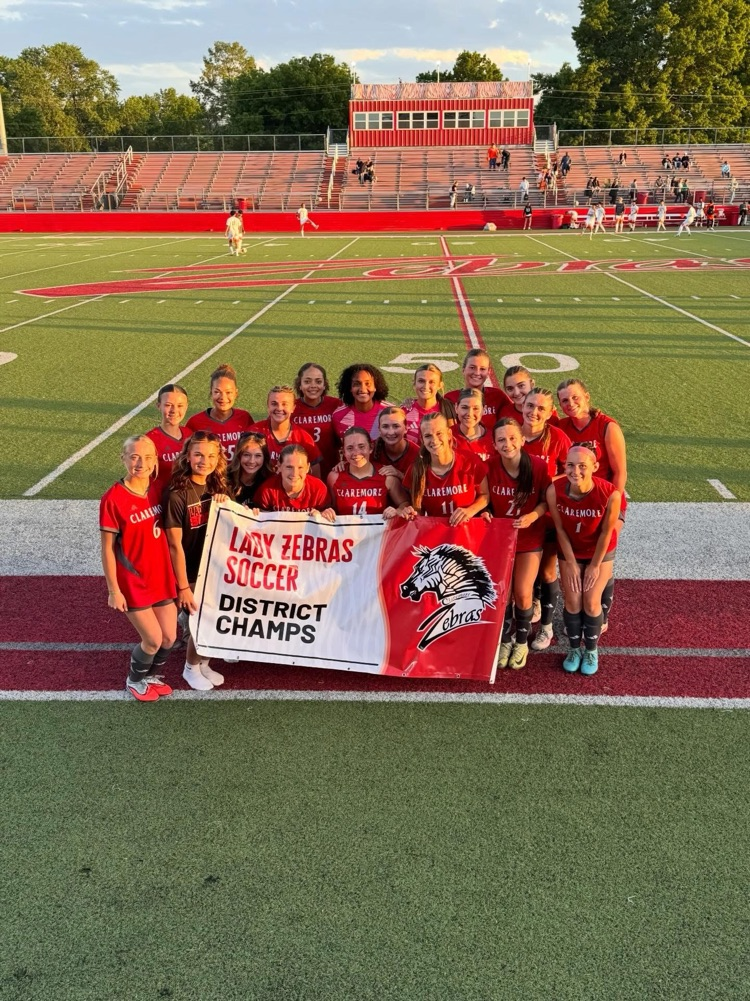 for all soccer team and uniform on the pitch holding a district championship sign