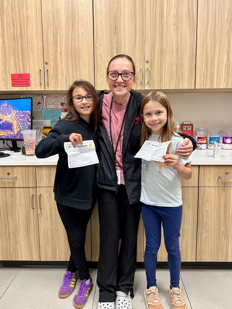 Nurse Kyla smiling with two students