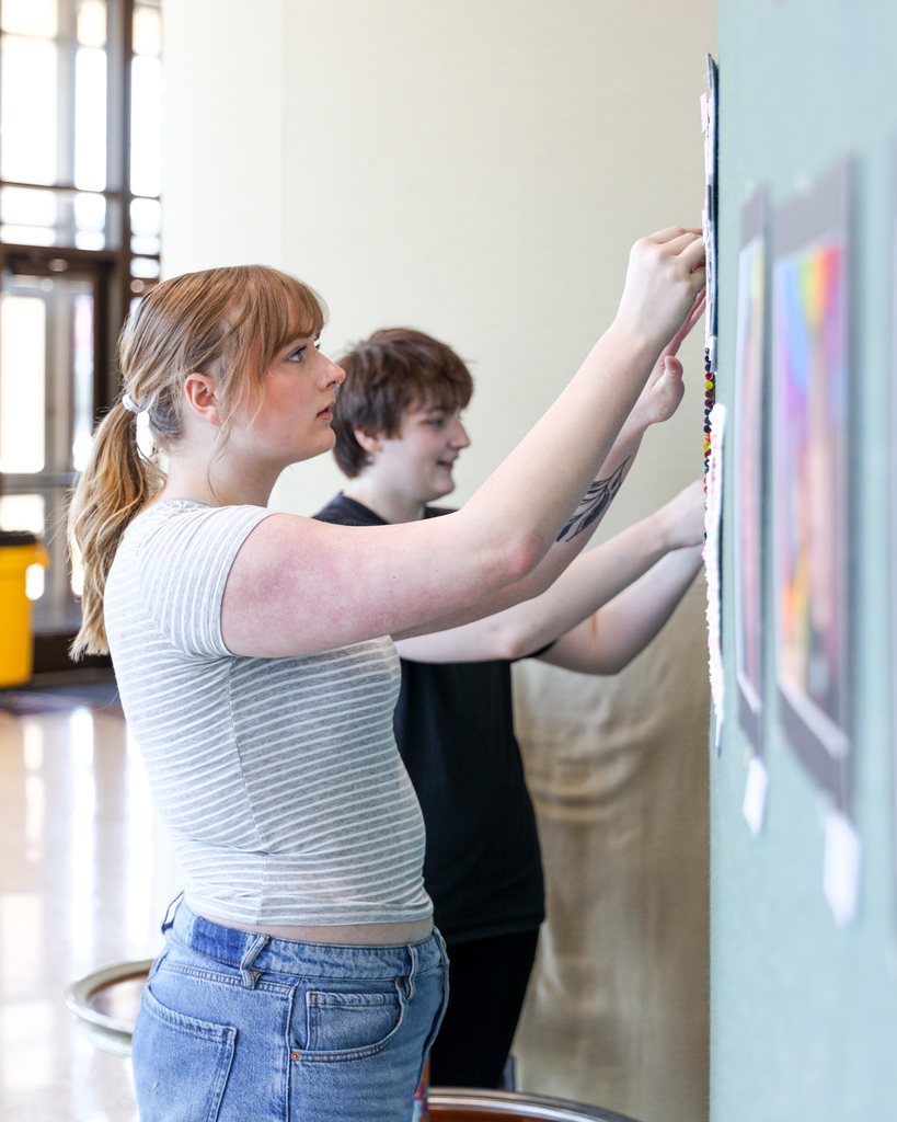 Art student hanging up their art for display
