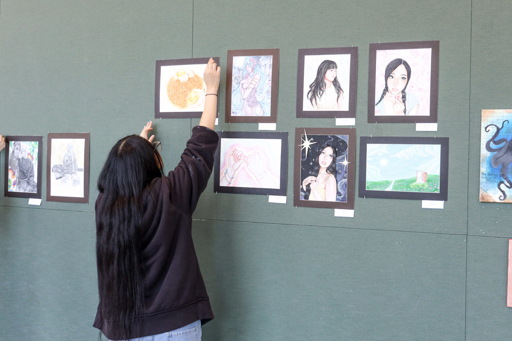 Art student hanging up their art for display