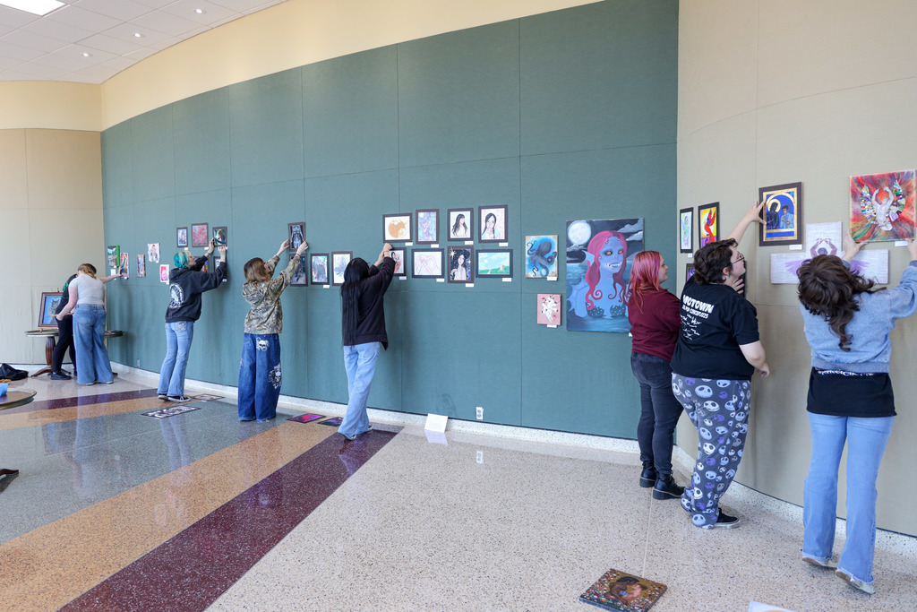 Art student hanging up their art for display