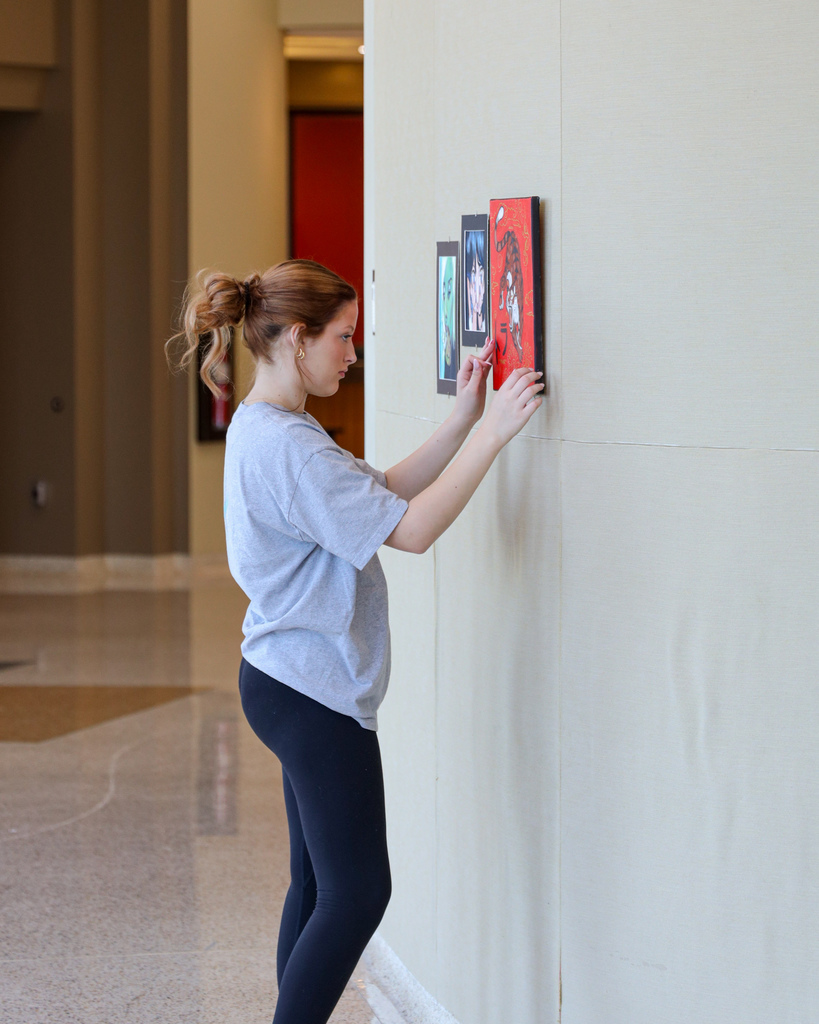 Art student hanging up their art for display