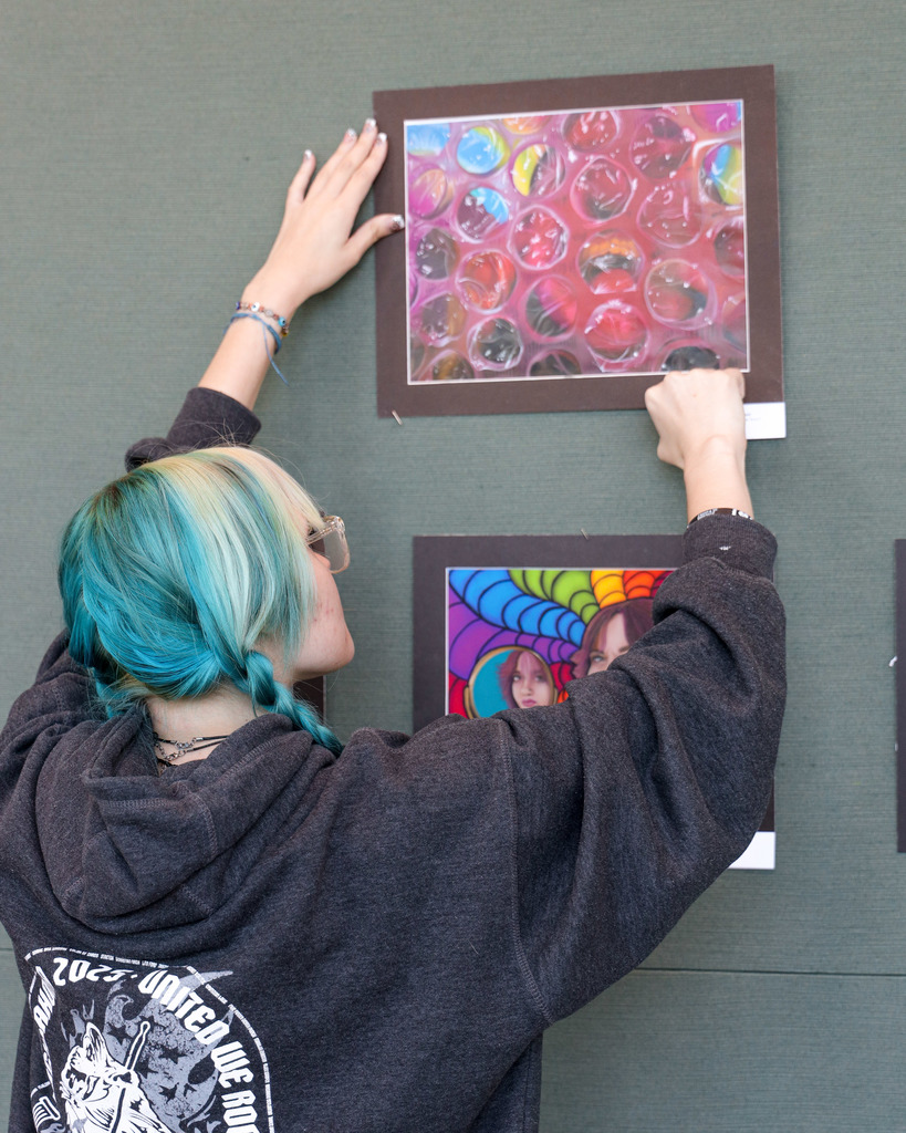 Art student hanging up their art for display