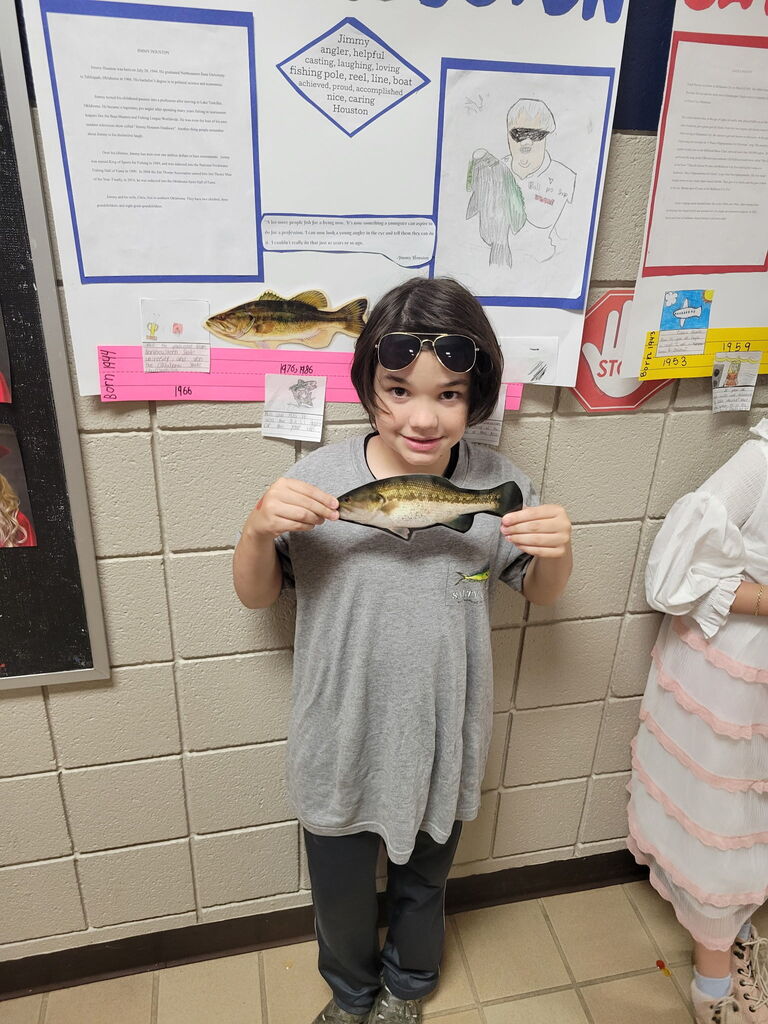 Student presenting for the wax museum, holding a fish