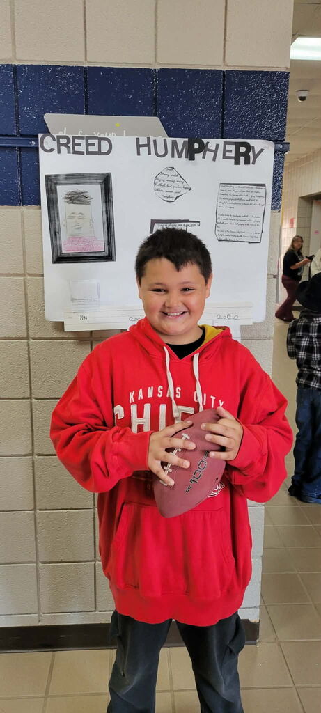 Student presenting for the wax museum, holding a football