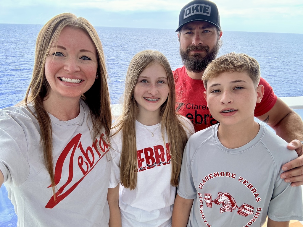 family in their zebra logo shirt on the bow of a cruise ship in the ocean. 
