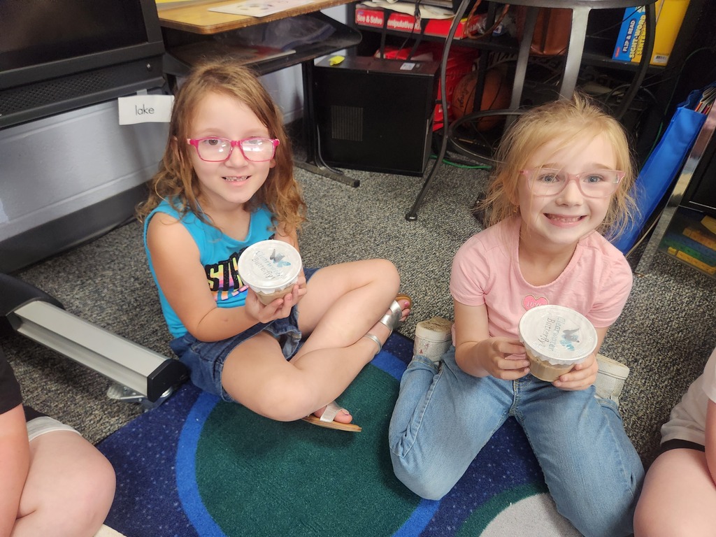 students holding catapillars and looking into cups