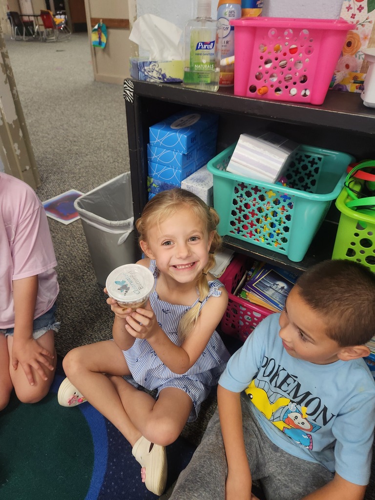 students holding catapillars and looking into cups