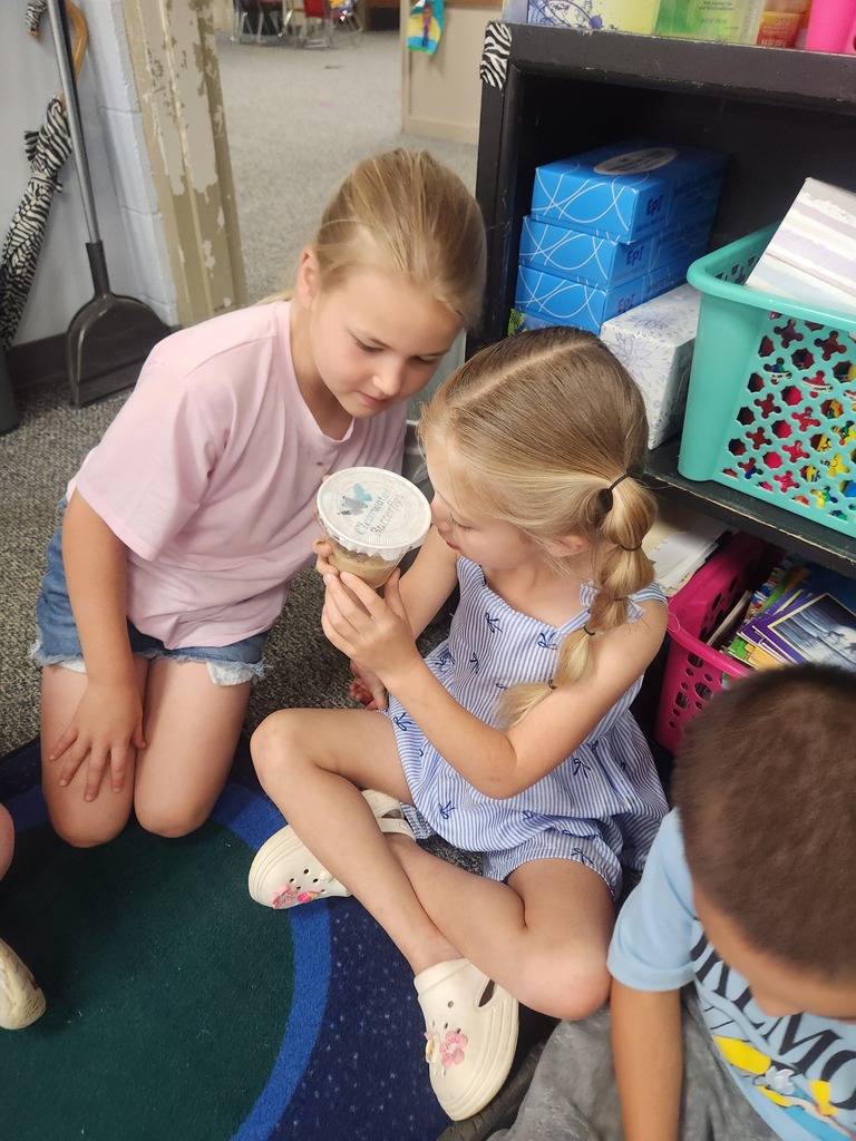 students holding catapillars and looking into cups