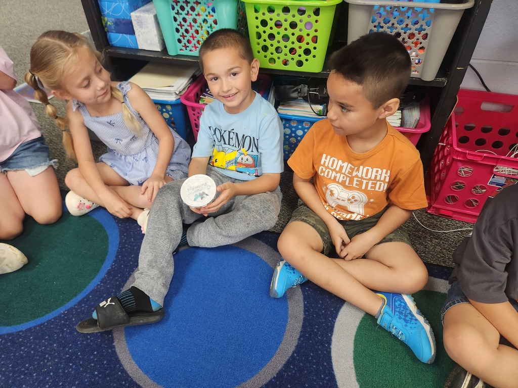 students holding catapillars and looking into cups