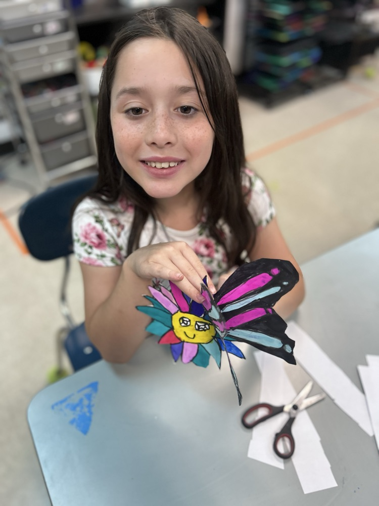 Student smiling with her butterfly in hand.