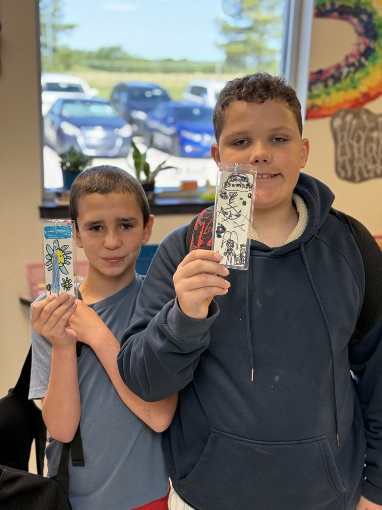 Students holding up their finished product while smiling.