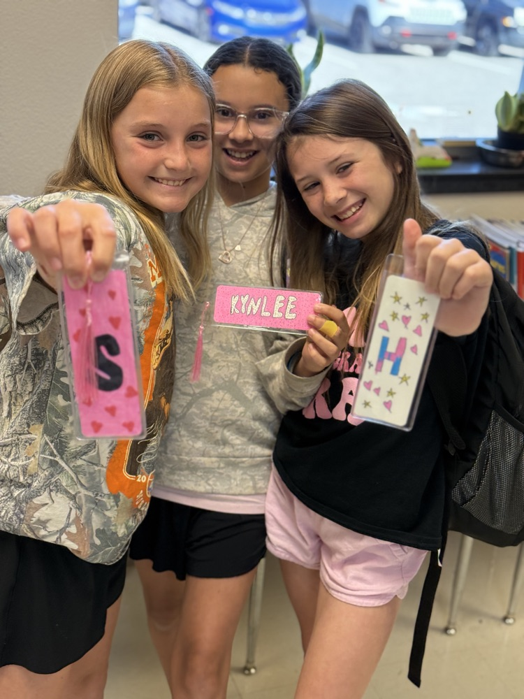 Students smiling while showing off their art work.