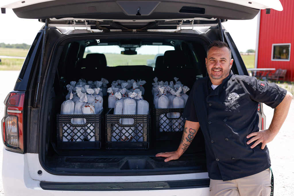 Ryan posing with crates of ground beef in the back of the suburban.