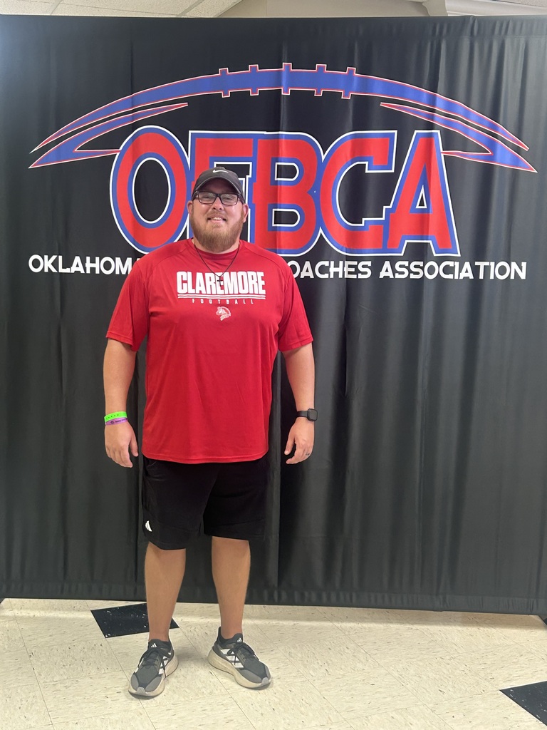Coach standing in front of an Oklahoma Football Coaches Association backdrop.