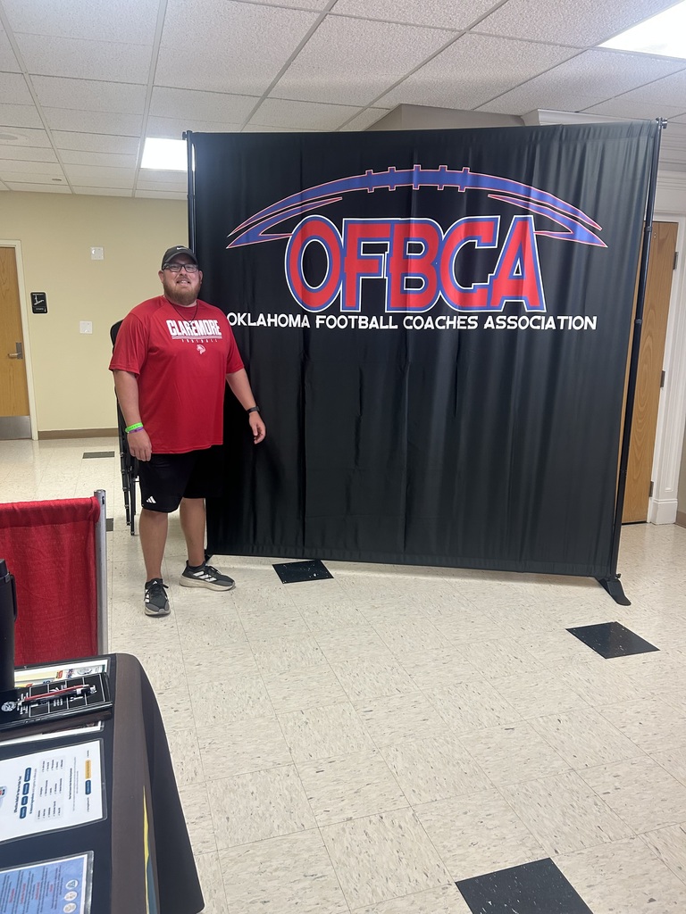Coach smiling in front of an Oklahoma Football Coaches Association backdrop.