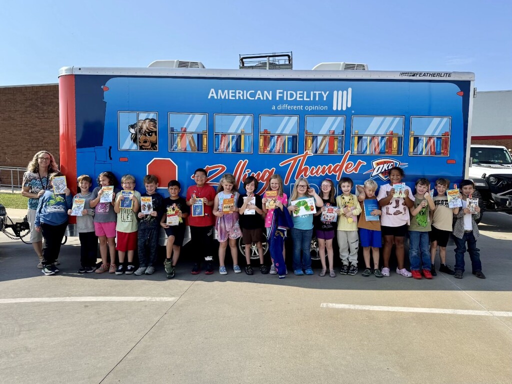 students smiling and holding books in front of bus