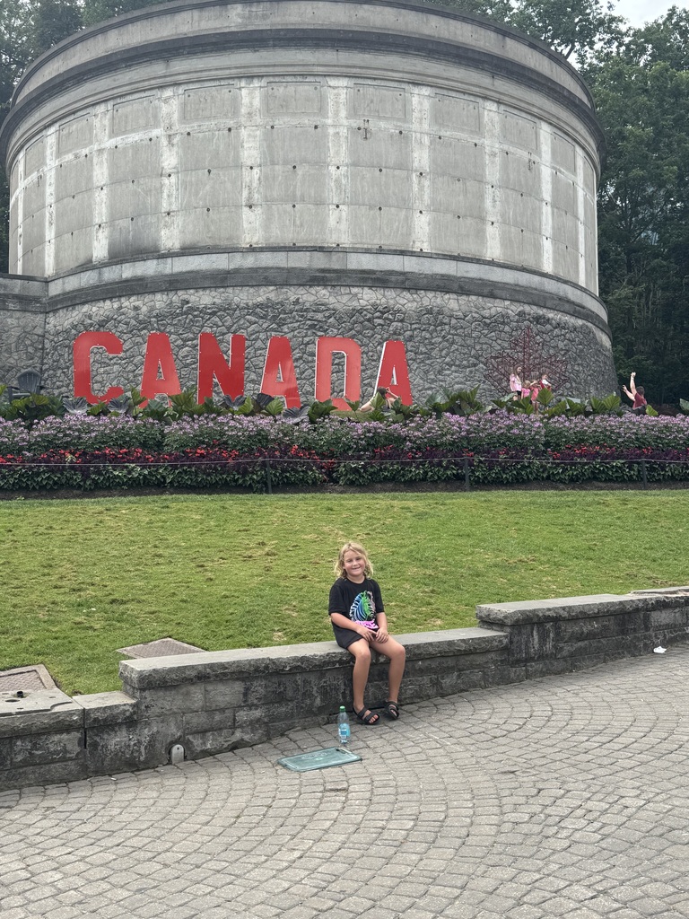 girl sitting in front of Canada sign