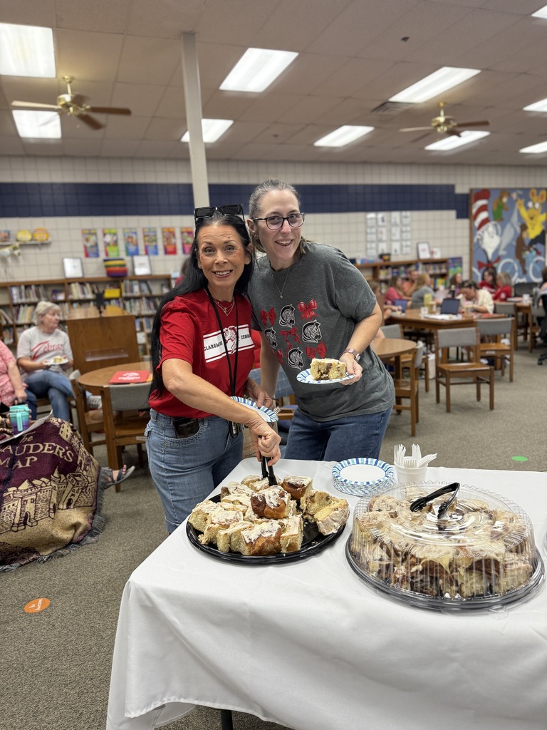 2 staff members getting cinnamon rolls and smiling