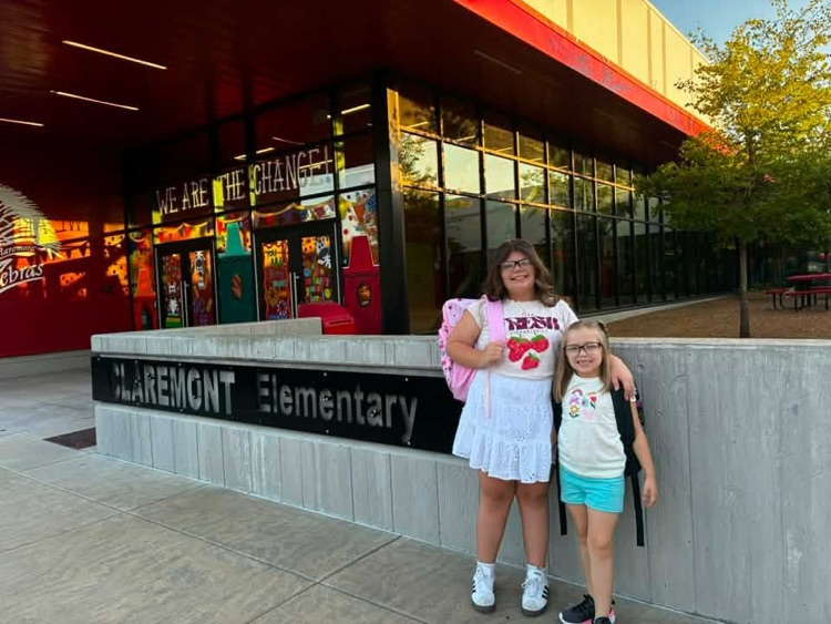students in front of school sign smiling 