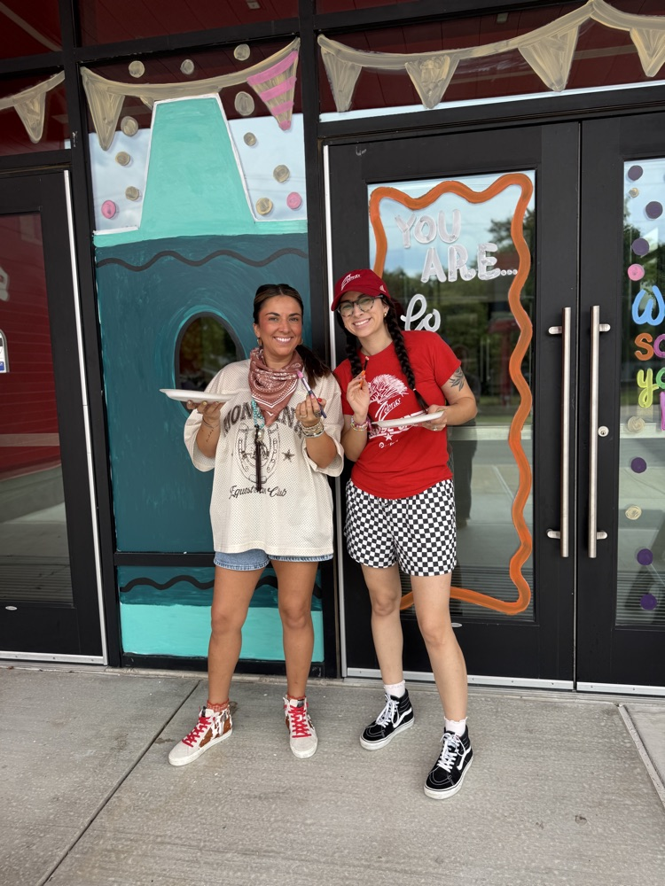Mrs. Baldwin and Mrs. Cunningham smiling in front of their painting 