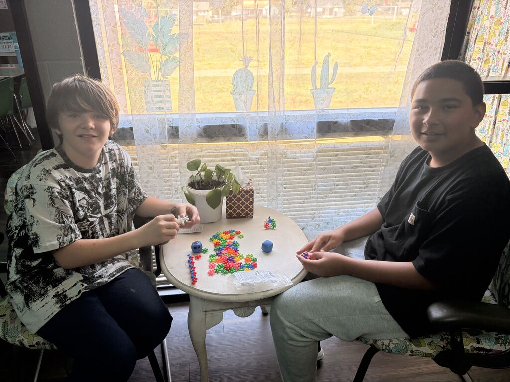 2 male students sitting at the table smiling
