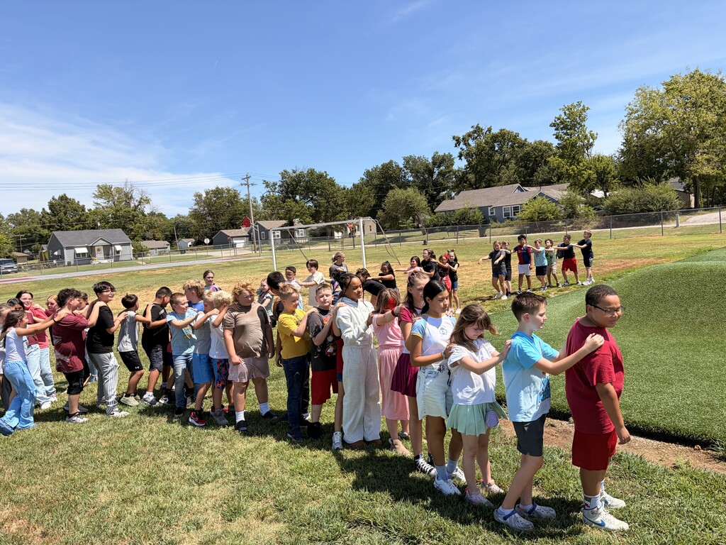 students standing in a line with hands on the persons should in front of them