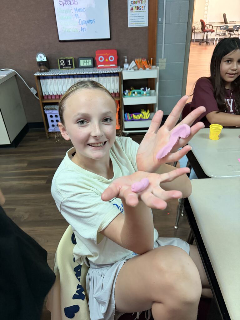 student holding play-doh smiling