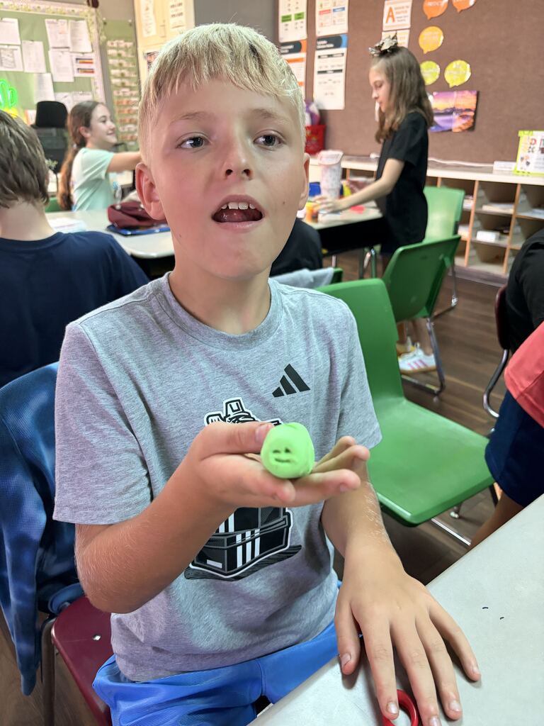 student holding green caterpillar