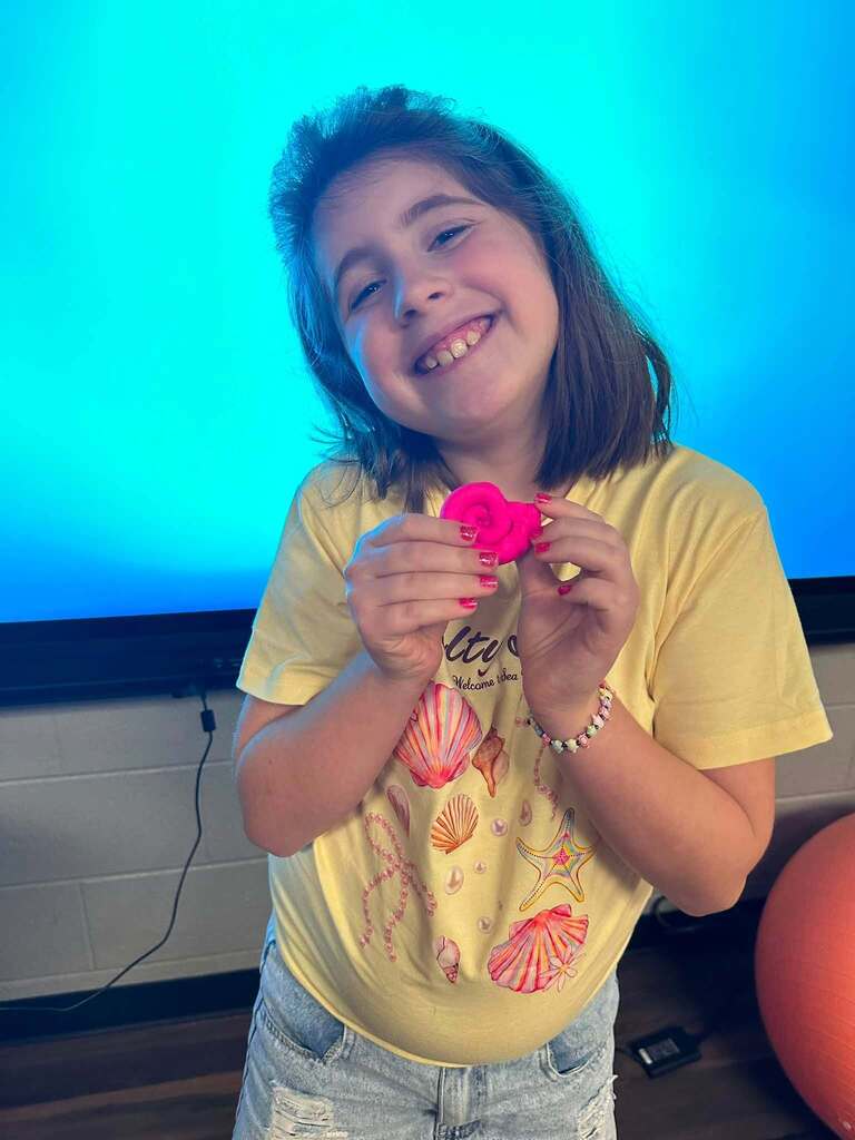 students smiling with her pink playdoh