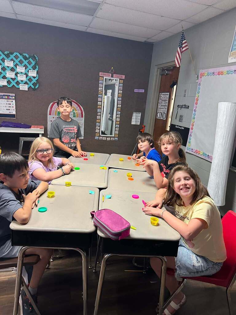 6 students smiling at the camera and sitting at the table