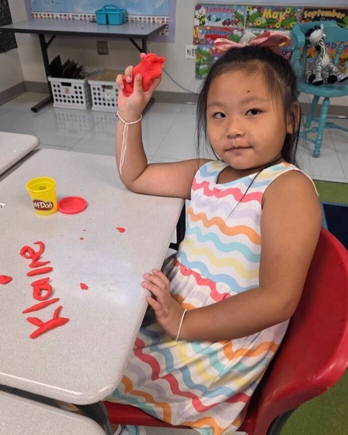 First grade student making their names out of playdough.