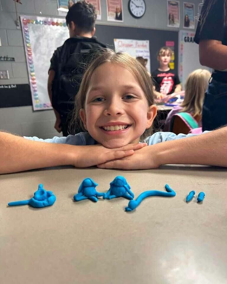 Fourth grade students showing off play doh creation of what brings them joy. 