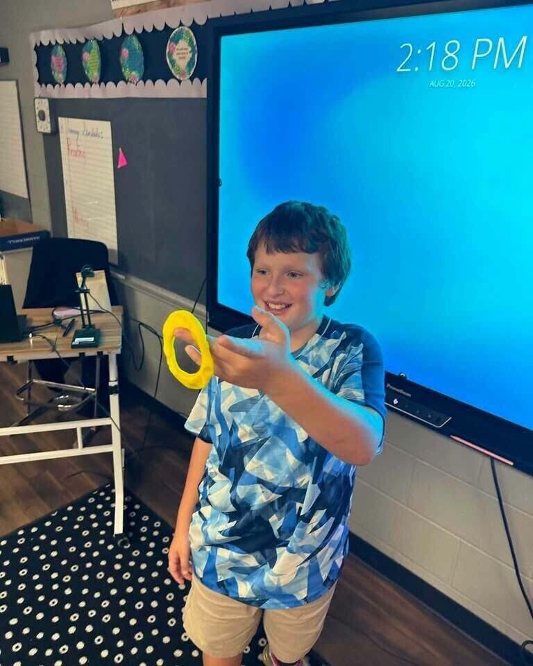 Fourth grade students showing off play doh creation of what brings them joy. 