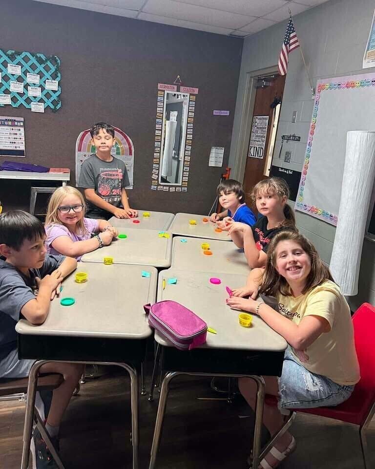 A group of fourth grade students sharing with each other their play doh creations.