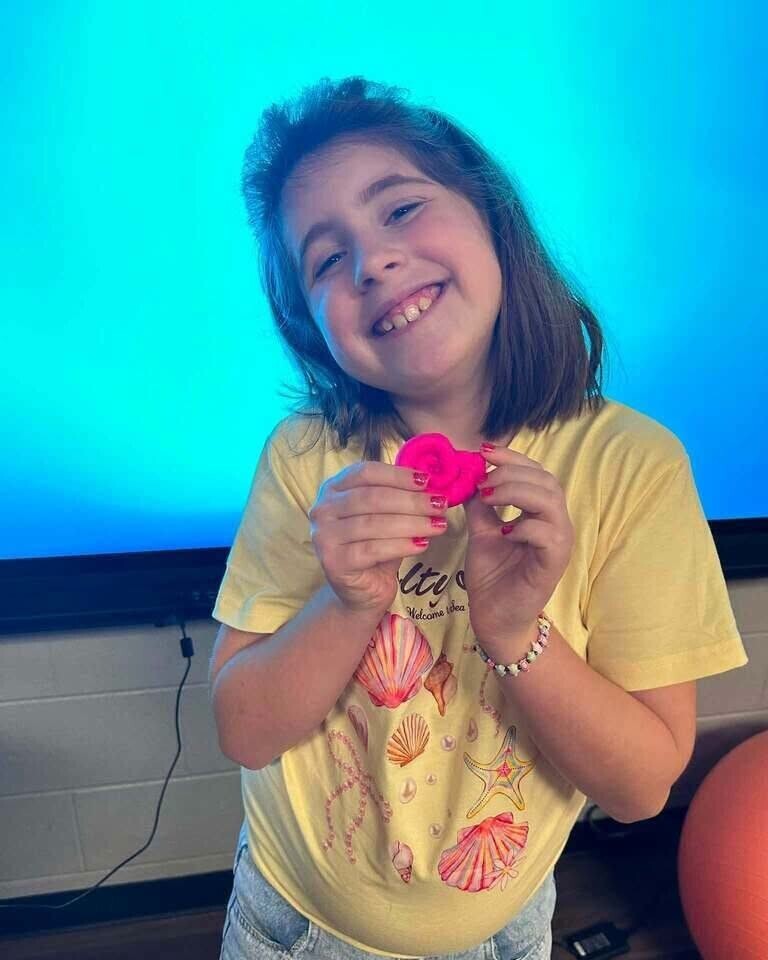 Fourth grade students showing off play doh creation of what brings them joy. 