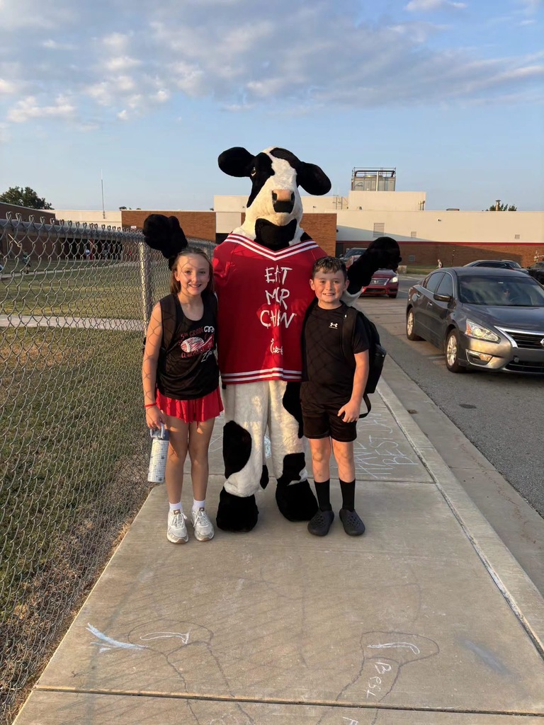 two students with the chick fil a cow, smiling