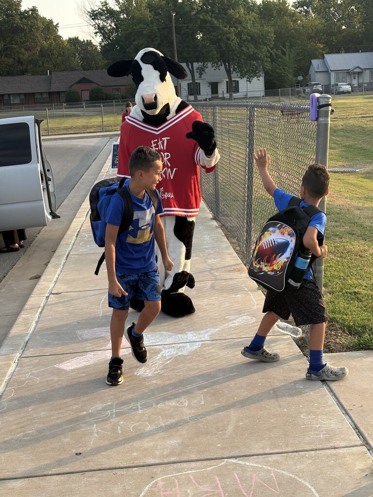 two students with the chick fil a cow, smiling