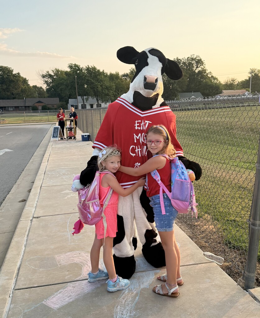 two students with the chick fil a cow, smiling