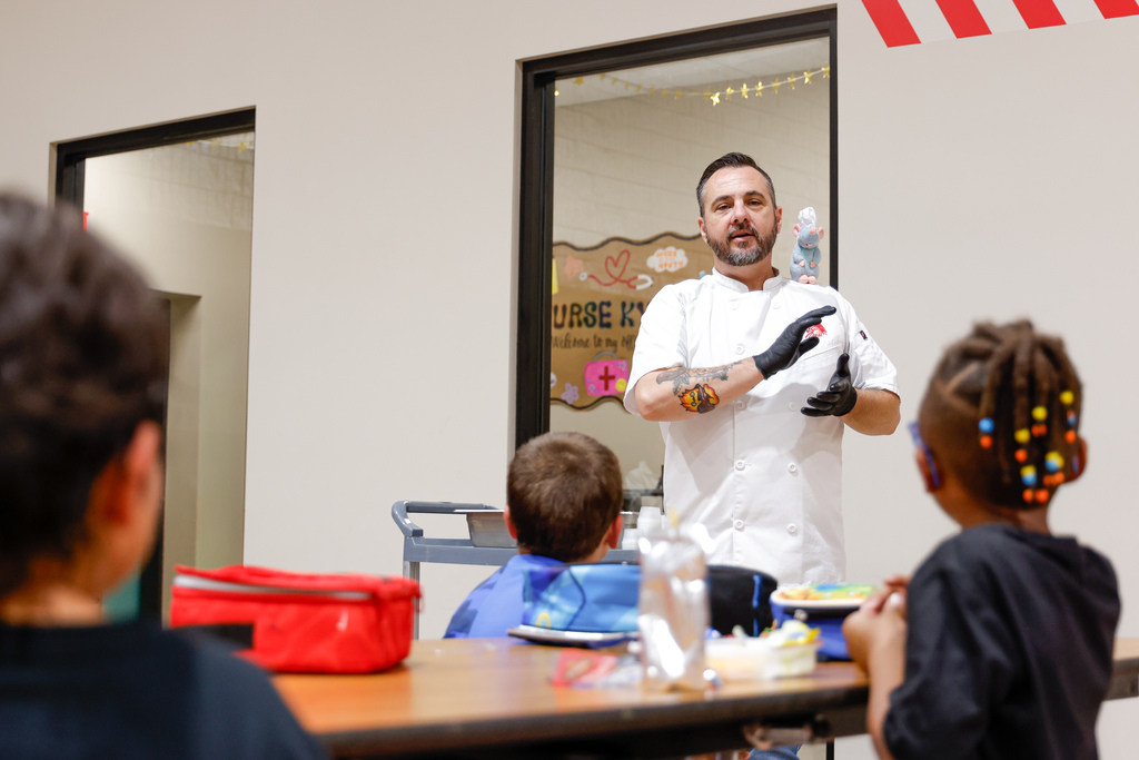 Chef Ryan presenting elementary students with squid ink pasta.